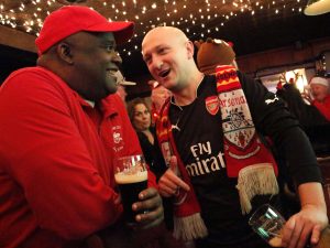 Ron Treausre (left), vocalist at Guns Don’t Run talks to Henry (Jamie) Behar (right), guitarist at Guns Don’t Run at O’hanlons Bar in Manhattan after a European soccer club, Arsenal game. They have known each other for more than 10 years through Arsenal, which led to Treasure’s inculcation into the punk rock band in 2015.