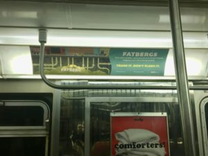 "Trash It, Don't Flush It" campaign poster in an NYC subway car