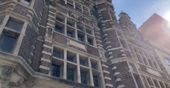 A shot of the Arcade's 3rd street Facade from a low angle. Sunlight fills the right edge of the frame, peeking between neighboring buildings.