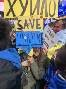 A woman holds a sign written in both English and Ukrainian