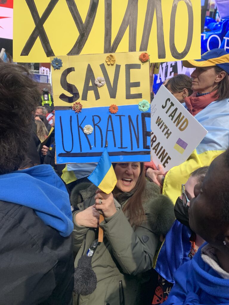 A woman holds a sign written in both English and Ukrainian