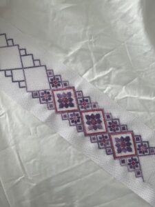 Needlework in progress with pink, purple and white colors