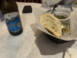White bread with chimichurri sauce and a Quilmes beer on a table at Boca Juniors Steakhouse