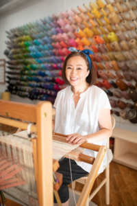 Yukako smiling on the loom equipment