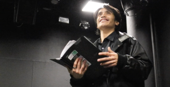NYU Tisch drama student Brandon Bautista stands in a film studio holding a script