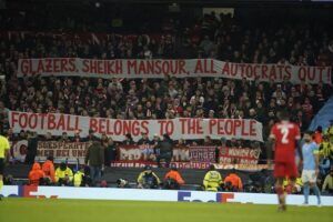 Bayern fans hold banners during the Champions League quarterfinal, first leg, soccer match between Manchester City and Bayern Munich at the Etihad stadium in Manchester, England, Tuesday, April 11, 2023. The banners say: glazers, sheikh mansour, all autocrats out, football belongs to the people. (AP Photo/Dave Thompson)