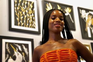 Woman standing in front of multiple pieces of artwork at a gallery