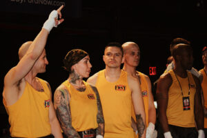 Nicole Malpeso, second from left, standing in line with her FDNY boxing teammates before a match in Terminal 5. All of the teammates are wearing yellow tank tops and Malpeso sports a bandana.