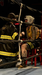 Nicole Malpeso sitting down between rounds with her FDNY boxing coach, who is giving her a pep talk.