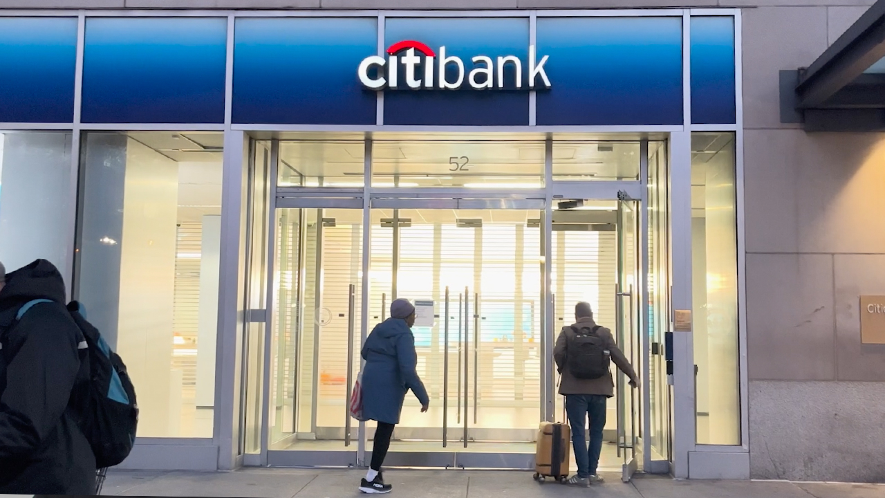 Two pedestrians walking into a Citibank