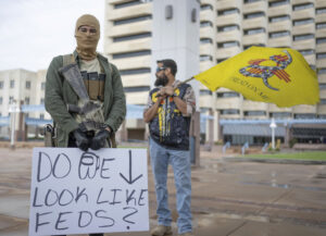 Individuals displays open carry firearm in Albuquerque, New Mexico at a Second Amendment Protest. One of the individuals is holding a "Don't Tread On Me" flag, which has been combined with the New Mexico state flag.