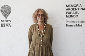 A woman standing against a white background with the words "Memoria Argentina Para El Mundo."