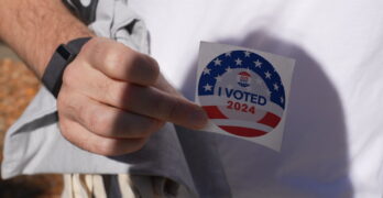 Close-up of a hand holding a 2024 "I Voted" sticker in New York City.